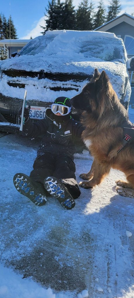 Photo by Robyn Bacchus / 10-year-old Roman and Lucy, a 3-year-old German shepherd, try to help clear snow from the family vehicle on Jan. 12.