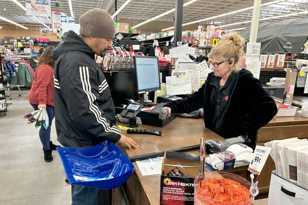 Right: Israel Najera of Sequim purchases a snow shovel and window scraper from Coastal Farm and Ranch cashier Darlene Nixon on Jan. 12. Najera estimated he had about 6 inches of snow at his home and needed tools to help remove it all.