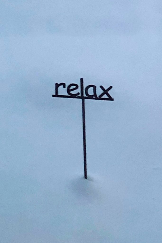 Photo by Janet Lenfant/ As snow covers its base, this sign encourages people to relax.
