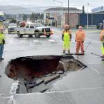 Photo by Keith Thorpe/Olympic Peninsula News Group / Port Angeles Public Works and Washington State Department of Transportation officials examine a sinkhole in the middle of Fifth and Lincoln streets in Port Angeles on Jan. 24 after water from a broken water main tore up the pavement.