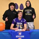 Sequim Gazette photo by Michael Dashiell / Sequims Jack Henninger on Feb. 7 signs a letter of intent to play at the University of Mary (North Dakota). The all-Olympic League kicker plans to study occupational therapy and kick for the Marauders football squad. Behind him (from left) Liam and Lars Wiker, his long snapper and kick holder.
