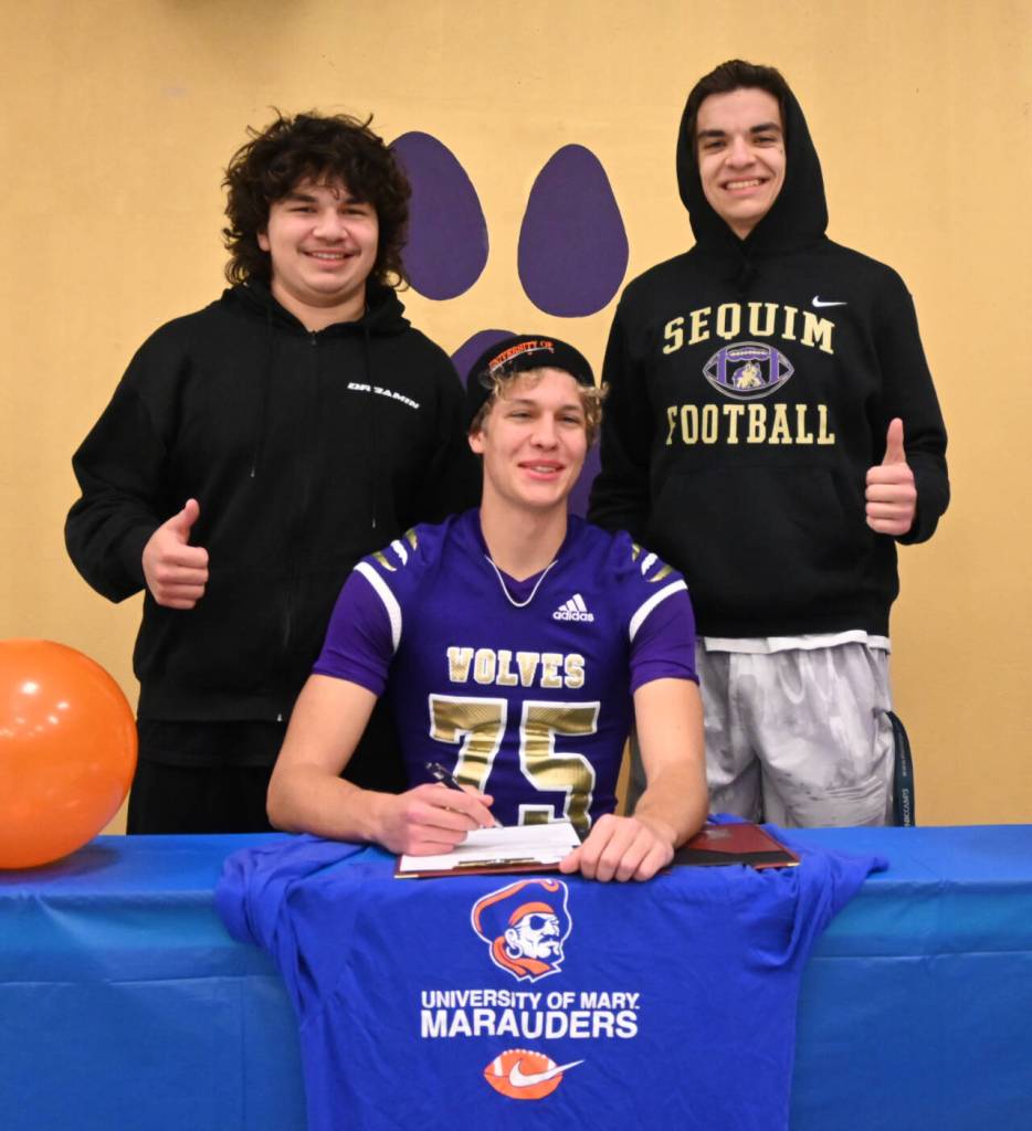 Sequim Gazette photo by Michael Dashiell / Sequims Jack Henninger on Feb. 7 signs a letter of intent to play at the University of Mary (North Dakota). The all-Olympic League kicker plans to study occupational therapy and kick for the Marauders football squad. Behind him (from left) Liam and Lars Wiker, his long snapper and kick holder.