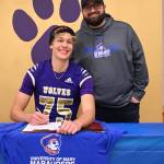 Sequim Gazette photo by Michael Dashiell / Sequims Jack Henninger on Feb. 7 signs a letter of intent to play at the University of Mary (North Dakota). The all-Olympic League kicker plans to study occupational therapy and kick for the Marauders football squad. Behind him is special teams coach Cody Buckmaster.