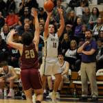 Sequim Gazette photo by Michael Dashiell / With Sequim coach Craig Brooks, right, looking on, Sequim's Lars Wiker takes a jump shot over Kingston's Dae'veon Swan in the Wolves' 63-50 win over the Buccaneers on Jan. 26.