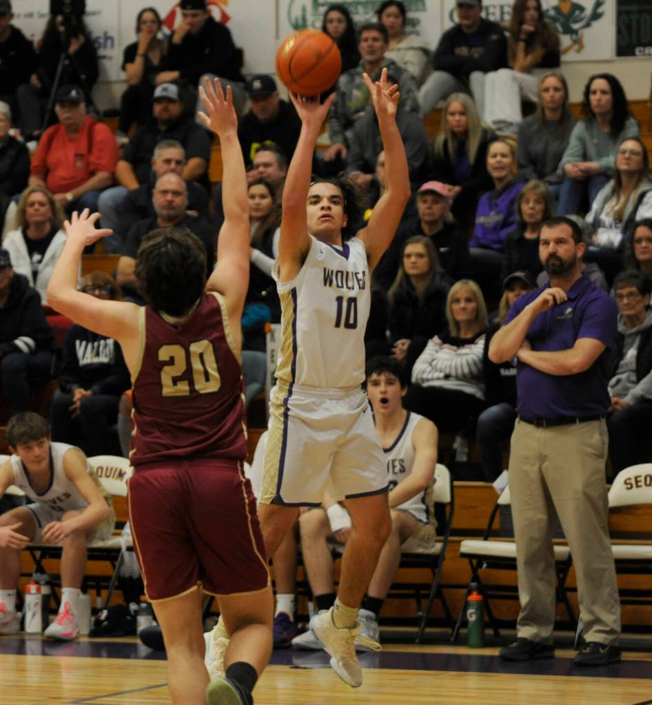 Sequim Gazette photo by Michael Dashiell / With Sequim coach Craig Brooks, right, looking on, Sequim's Lars Wiker takes a jump shot over Kingston's Dae'veon Swan in the Wolves' 63-50 win over the Buccaneers on Jan. 26.