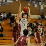 Sequim Gazette photo by Michael Dashiell / Sequim's Jamison Gray, center, takes a jumper over Kingston's Dae'veon Swan in the fourth quarter of a 63-50 SHS victory on Jan. 26.