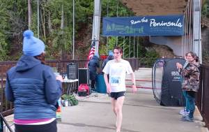 Men's 5K winner Langdon Larson of Port Angeles crosses the finish line at the Elwha Bridge Run held Saturday morning. (Pierre LaBossiere/Peninsula Daily News)