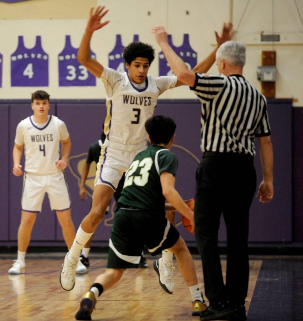 Sequim Gazette photo by Michael Dashiell / Sequims Solomon Sheppard, center, defends Evergreens Miguel Delgado in the first half of the Wolves 73-61 bi-district tournament win on Feb. 13. Looking on is Sequims Keenan Green.