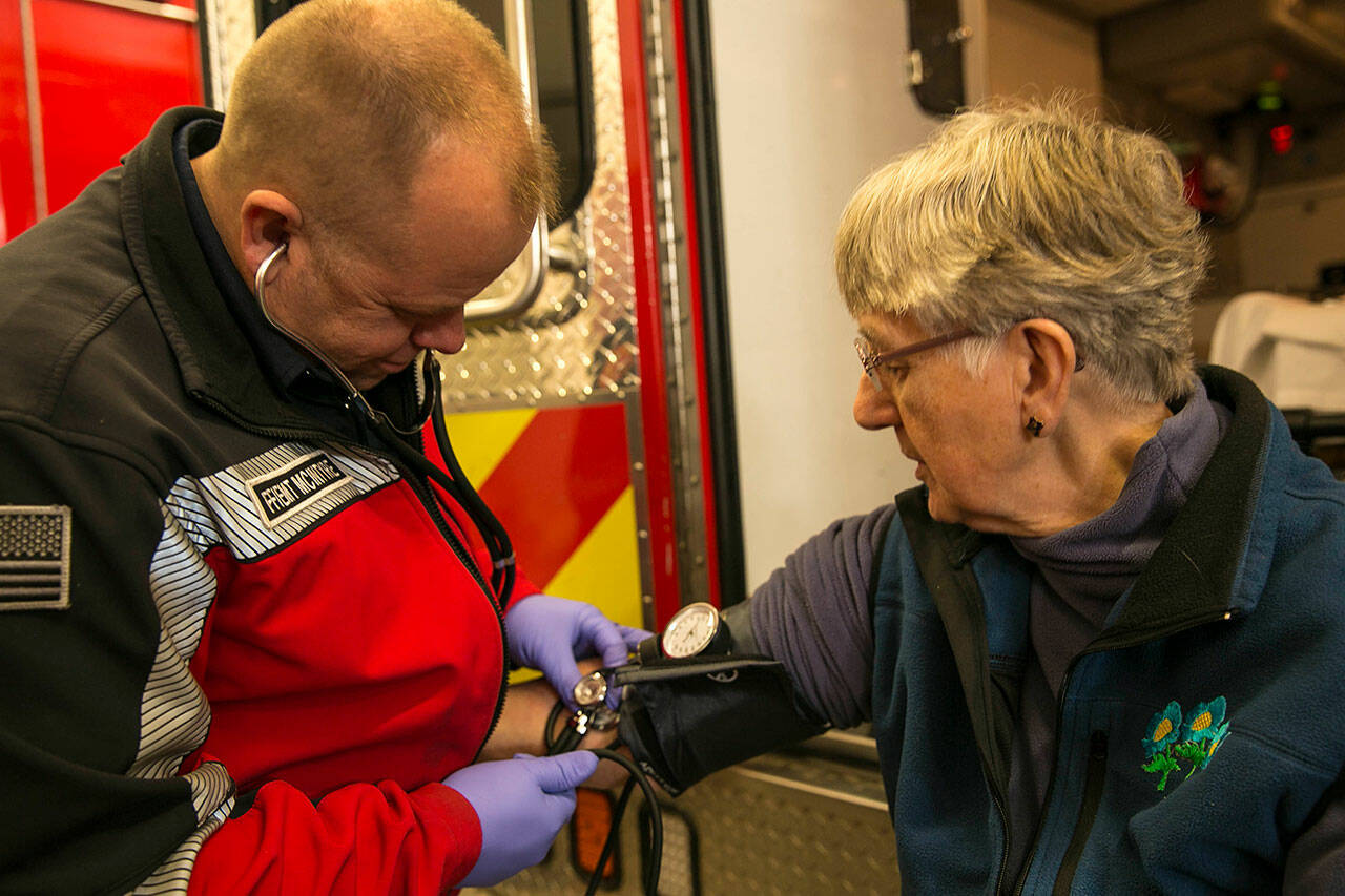 Photo courtesy Clallam County Fire District 3/ District leaders are considering implementing a community paramedic program that would help community members connect with needed services after non-emergency 9-1-1 calls. Pictured, firefighter/EMT John McIntyre with Clallam County Fire District 3 measures the blood pressure of Priscilla Hudson.