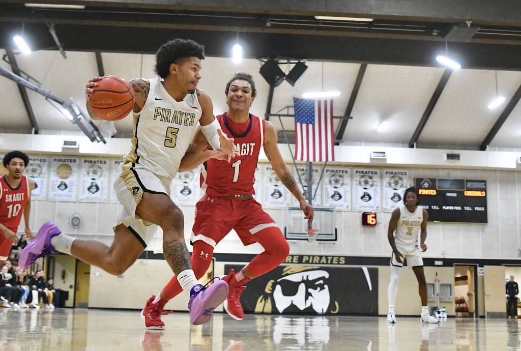 Photo by Jay Cline/Peninsula College / Peninsulas Javon Ervin, left, looks to score as he and the Pirates take on Skagit Valley on Feb. 21. The visiting Cardinals won 86-64, despite Ervins 32 points.