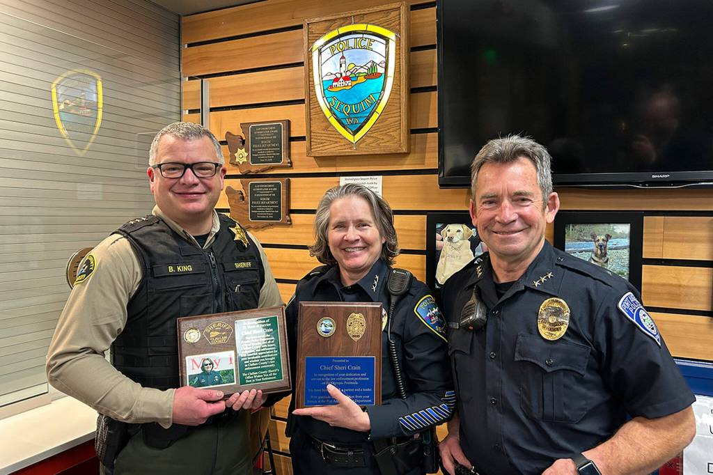 Sequim Gazette photo by Matthew Nash/ Sequim Police Chief Sheri Crain stands with plaques she received from Clallam County Sheriff Brian King and Port Angeles Police Chief Brian Smith.