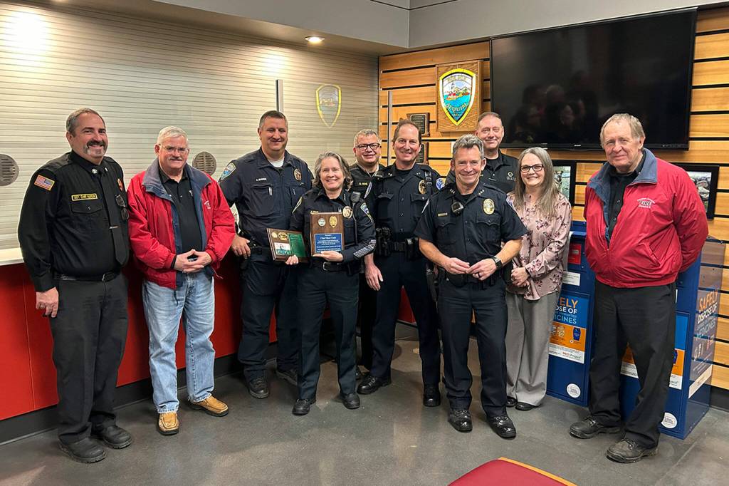 Sequim Gazette photo by Matthew Nash/ First responders stand with Sequim police chief Sheri Crain after a proclamation was read at the Feb. 26 city council meeting honoring her service in the city.