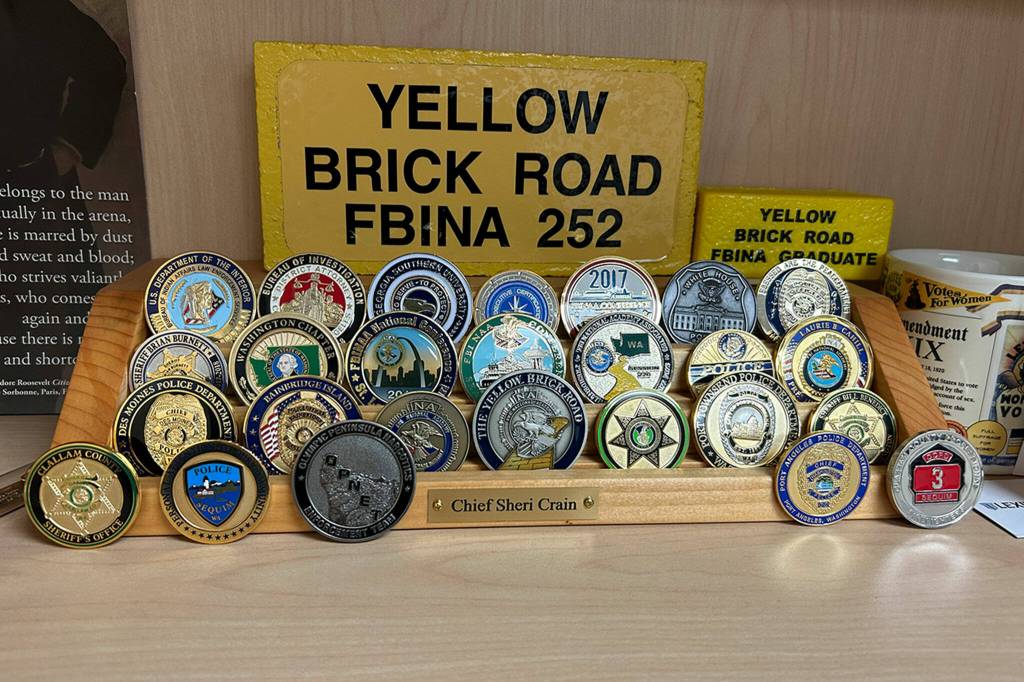 Sequim Gazette photo by Matthew Nash/ Sheri Crains shelf features many challenge coins shes received through her 33-year career.