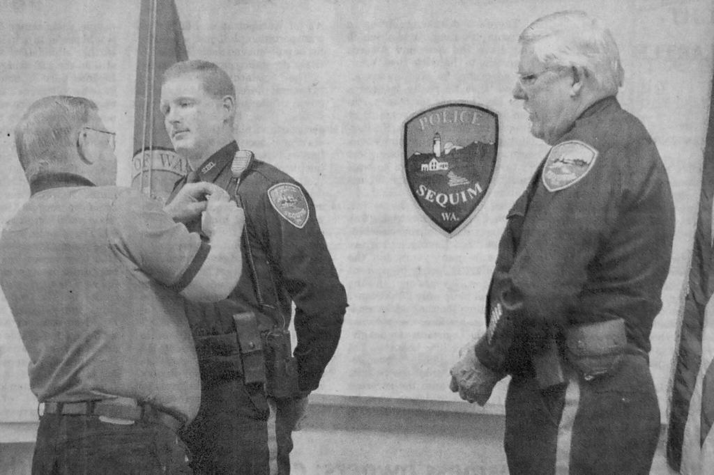 Sequim Gazette file photo by Michael Dashiell / Mike Hill receives a pin from his father after being sworn in as a full-time officer in early August 2001. The 24-year-old had served as a reserve officer for three years. Looking on is then Sequim Police chief Byron Nelson.