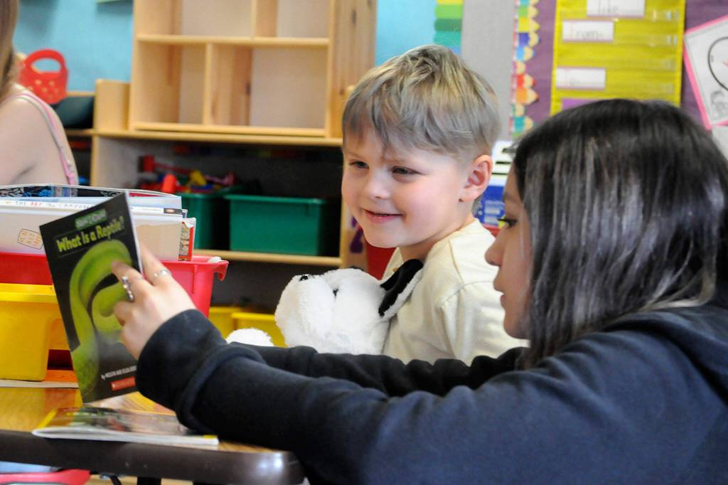 At left: Greywolf Elementary kindergartener Caspian Savage and Sequim Middle School eighth grader Angie Torres enjoy a book about reptiles on March 1.