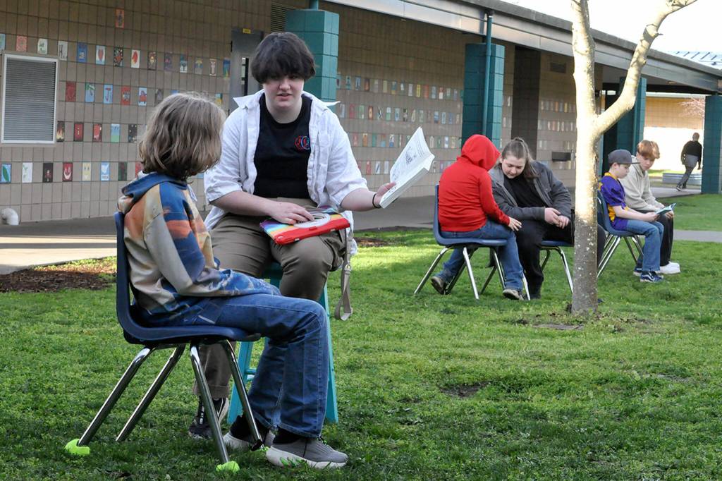 Sequim Gazette photo by Matthew Nash/ Sequim High Schooler Sabrina Herbelin reads with Helen Haller Elementary fifth grader Tristin Theilen-Morrison alongside a few other students braving a chilly morning on March 1 for Sequim School Districts celebration of Read Across America Day.