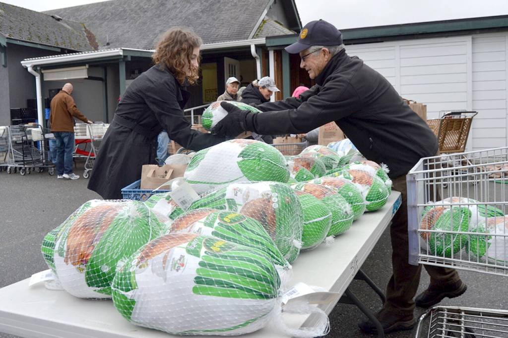 Sequim Gazette file photo by Matthew Nash / Anna Ito of Sequim receives a turkey from Bob Macaulay, president of the Rotary Club of Sequim at the Sequim Food Bank in November 2018. Members of Sequim Noon Rotary, along with Sequim Sunrise Rotary and Trinity United Methodist Church, helped hand out Holiday Meal Bags to dozens of community members that day.