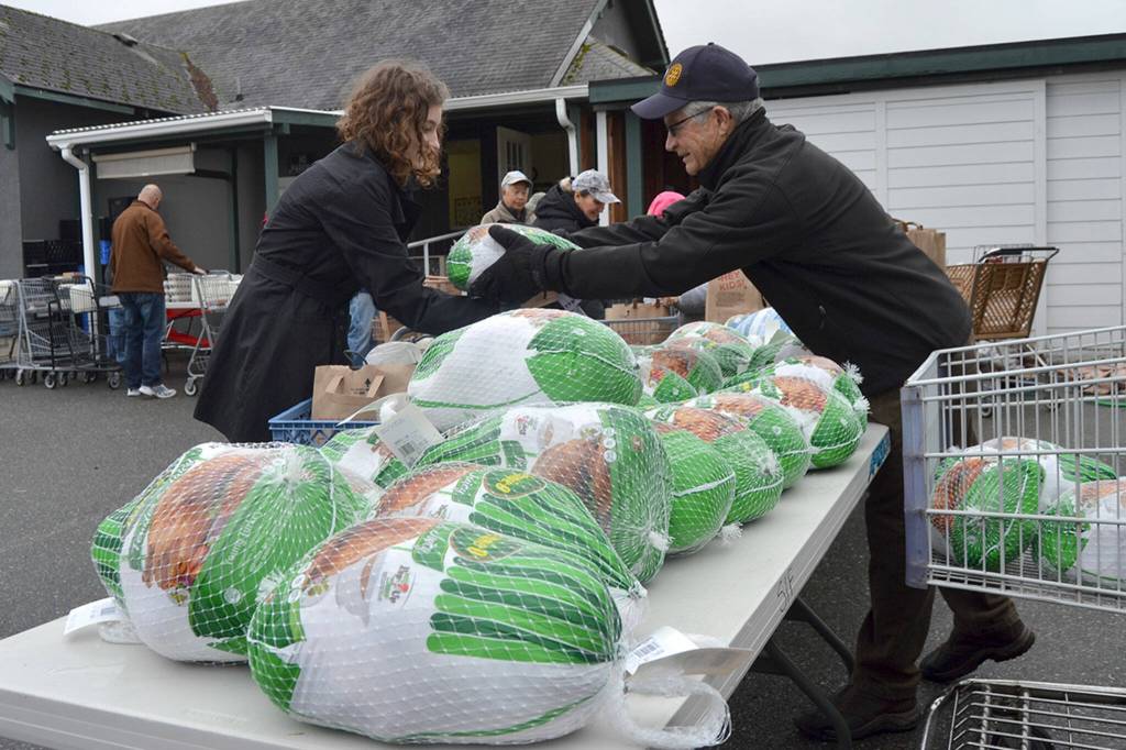Sequim Gazette file photo by Matthew Nash / Anna Ito of Sequim receives a turkey from Bob Macaulay, president of the Rotary Club of Sequim at the Sequim Food Bank in November 2018. Members of Sequim Noon Rotary, along with Sequim Sunrise Rotary and Trinity United Methodist Church, helped hand out Holiday Meal Bags to dozens of community members that day.