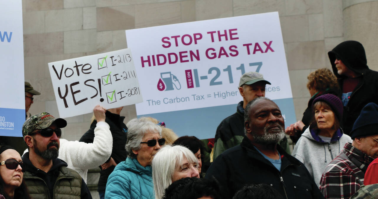 Photo by Aspen Anderson/Washington State Journal / Protestors and signature gatherers on the citizen initiatives gather on the capitol steps, with some holding signs to Stop the hidden gas tax.