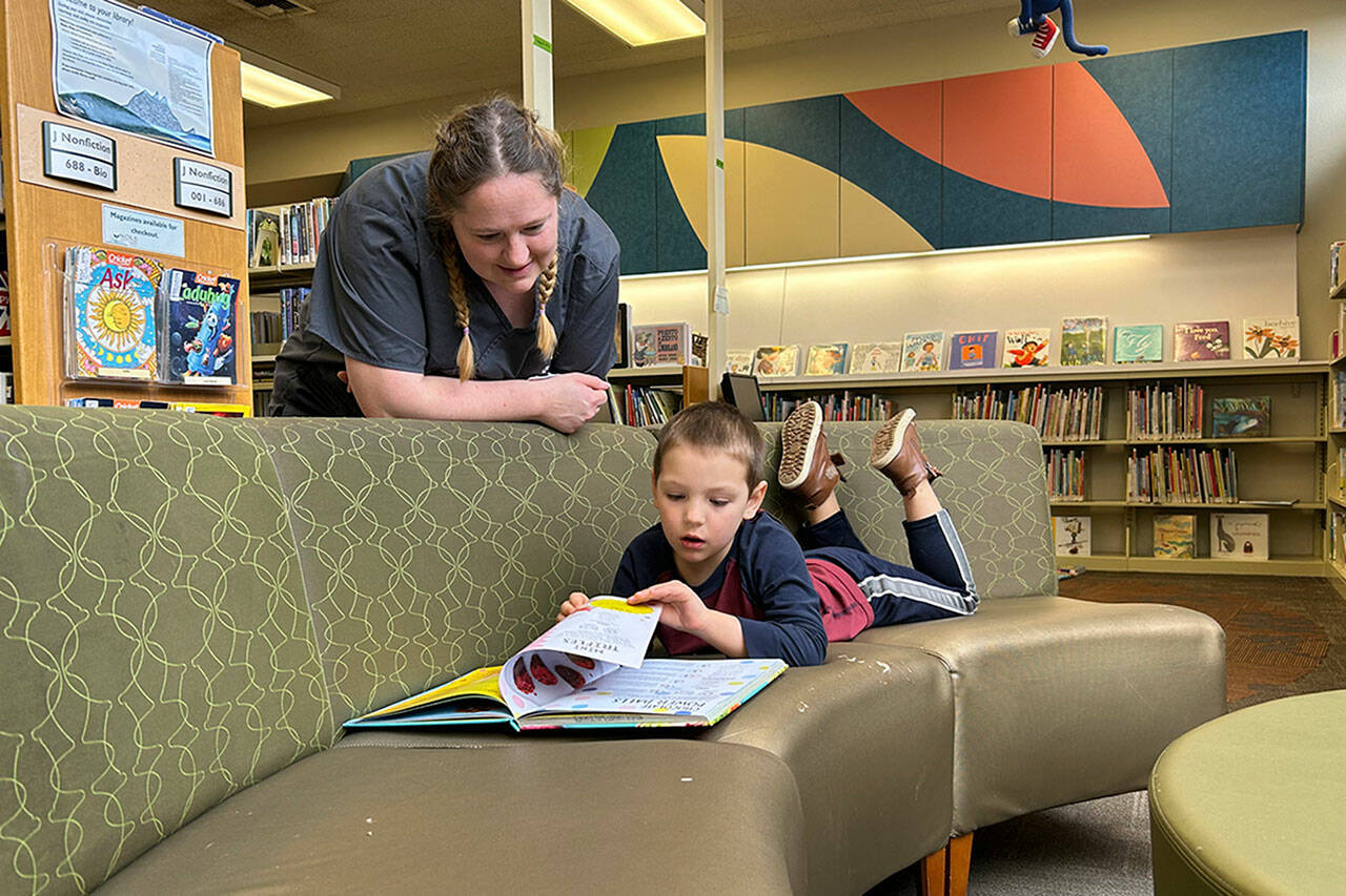 Sequim Gazette photo by Matthew Nash
Rachel Tax talks to her four-year-old son AJ while he reads a book in the childrens section of the Sequim Library on March 9. She said they visited one last time before it closes temporarily for construction so that her daughter Anna-Marie could check out some cat books for a 4-H report.