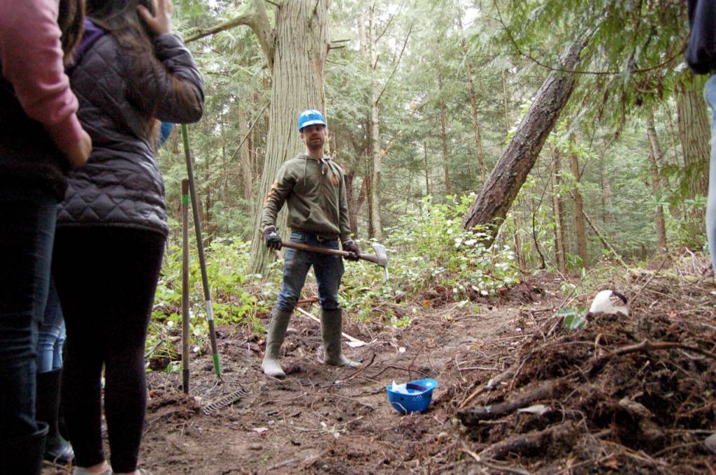Sequim Gazette file photo by Matthew Nash / Powell Jones, executive director of the Dungeness River Audubon Center, shows students how to use tools like a McLeod for clearing trail in 2017.