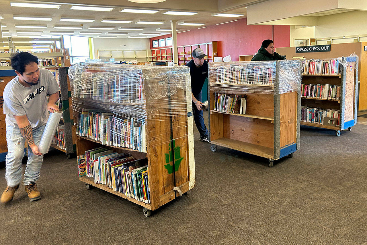Sequim Gazette photo by Matthew Nash
Olympic Moving and Storage of Lakewood crew, from left, Sala, David Qualls, relocation consultant, and Seela Afia wrap carts filled with books on March 16 inside the Sequim Library as they prepare to move its contents to a temporary space during construction.