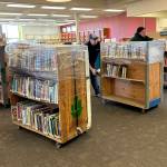Sequim Gazette photo by Matthew Nash
Olympic Moving and Storage of Lakewood crew, from left, Sala, David Qualls, relocation consultant, and Seela Afia wrap carts filled with books on March 16 inside the Sequim Library as they prepare to move its contents to a temporary space during construction.