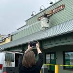 Sequim Gazette photo by Matthew Nash/ Bruce Miller, owner of Miller Signs, places the Sequim Library sign on March 22 outside the temporary building at 609 W. Washington St., Suite 21 as Corrina Desmarais, older adult services librarian, takes a video. Miller Signs former owner Rob Campbell built the sign in 2009 for the remodel of the current library at 630 N. Sequim Ave. The library is set for expansion and renovation through the next year.