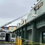 Sequim Gazette photo by Matthew Nash/ Bruce Miller, owner of Miller Signs, places the Sequim Library sign on March 22 outside the temporary building at 609 W. Washington St., Suite 21. Miller Signs former owner Rob Campbell, on left, built the sign in 2009 for the remodel of the current library at 630 N. Sequim Ave. The library is set for expansion and renovation through the next year.