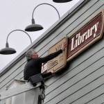 Sequim Gazette photo by Matthew Nash
Bruce Miller, owner of Miller Signs, places the Sequim Library sign on March 22 outside the temporary building at 609 W. Washington St., Suite 21. Miller Signs former owner Rob Campbell built the sign in 2009 for the remodel of the current library at 630 N. Sequim Ave. The library is set for expansion and renovation through the next year.