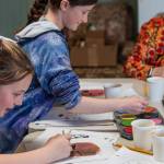 Photo by Emily Matthiessen / Chief make-up artist Addie Slezak and friend Macee Warner work on designs with Judy Griffin for the upcoming production Plays From African Folktales. Slezak is one of six participants in the two-week theater program who chose to work on tech backstage while the other 19 children will perform the play for local audiences.