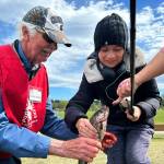 Barry Baker, a volunteer with the North Olympic Peninsula Chapter of Puget Sound Anglers, helps Christian Stevenson, 11, of Port Ludlow, take the hook out of his recently caught fish at Kids Fishing Day. It was Stevensons second fish of the day, he said.