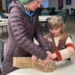 Photo courtesy Heidi Krzyworz/ Mother and daughter Emily Carlquist and Iris Carlquist-Bundy work together to make a cat scratcher with boxes used to hold Girl Scout cookies during an activity with Girls Scouts with Troop 45181.