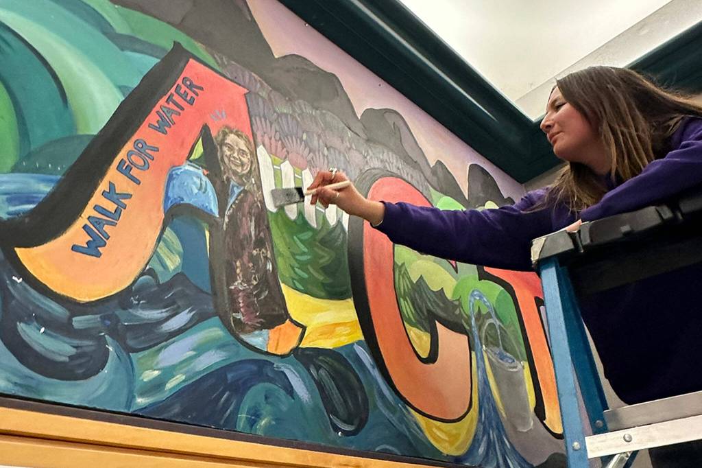 Photo courtesy Chelsea Reichner/ Melia Nelson, a junior at Sequim High School, puts a finishing touch on the Interact Club mural in H-building in March. It was started by 2020 grad Alissa Lofstrom and continued by 2023 grad Rae Douglas. Nelson painted a picture of Lofstrom in the A to honor the memory of her after she died in 2021.