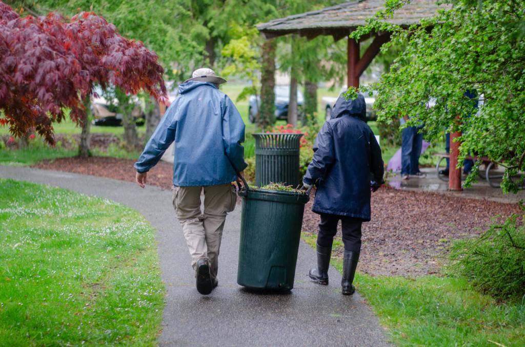 Sequim Gazette photo by Elijah Sussman / Volunteer landscapers carry a barrel of organic material at Carrie Blake Community Park during the Sequim Beautiful Day event on April 27.