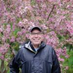 Sequim Gazette photo by Elijah Sussman / Sequim Beautiful Day organizer Rick Dietzman, known to some as Reverend Go, stands in front of wet spring bloom at Carrie Blake Community Park on April 27.
