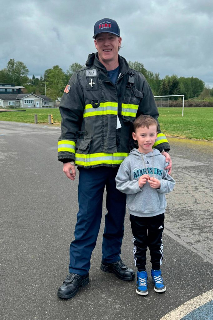 Photo courtesy Sequim Elementary PTA/ Captain Jack Hueter with Clallam County Fire District 3 stands with his son Ellis during Friend a First Responder Day on April 26 at Greywolf Elementary.