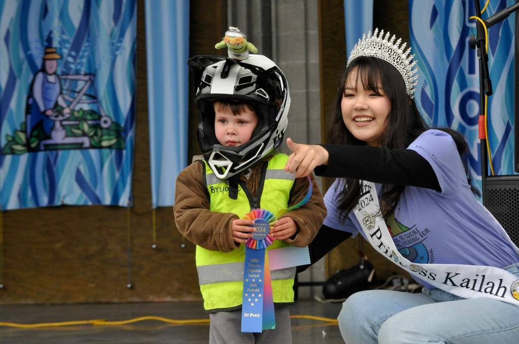 Sequim Gazette photo by Matthew Nash/ Bryant Volker smiles for Irrigation Festival photographer Keith Ross during the Kids Parade awards with help from festival Princess Kailah Blake. He won first place for his bicycle float.