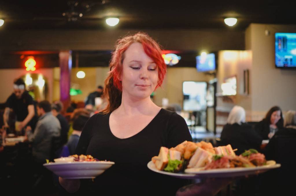 Sequim Gazette photo by Elijah Sussman / Server Amber Melcer delivers a sandwich with tater tots, and a salad at The Oasis Bar and Grill in Sequim on May 5.