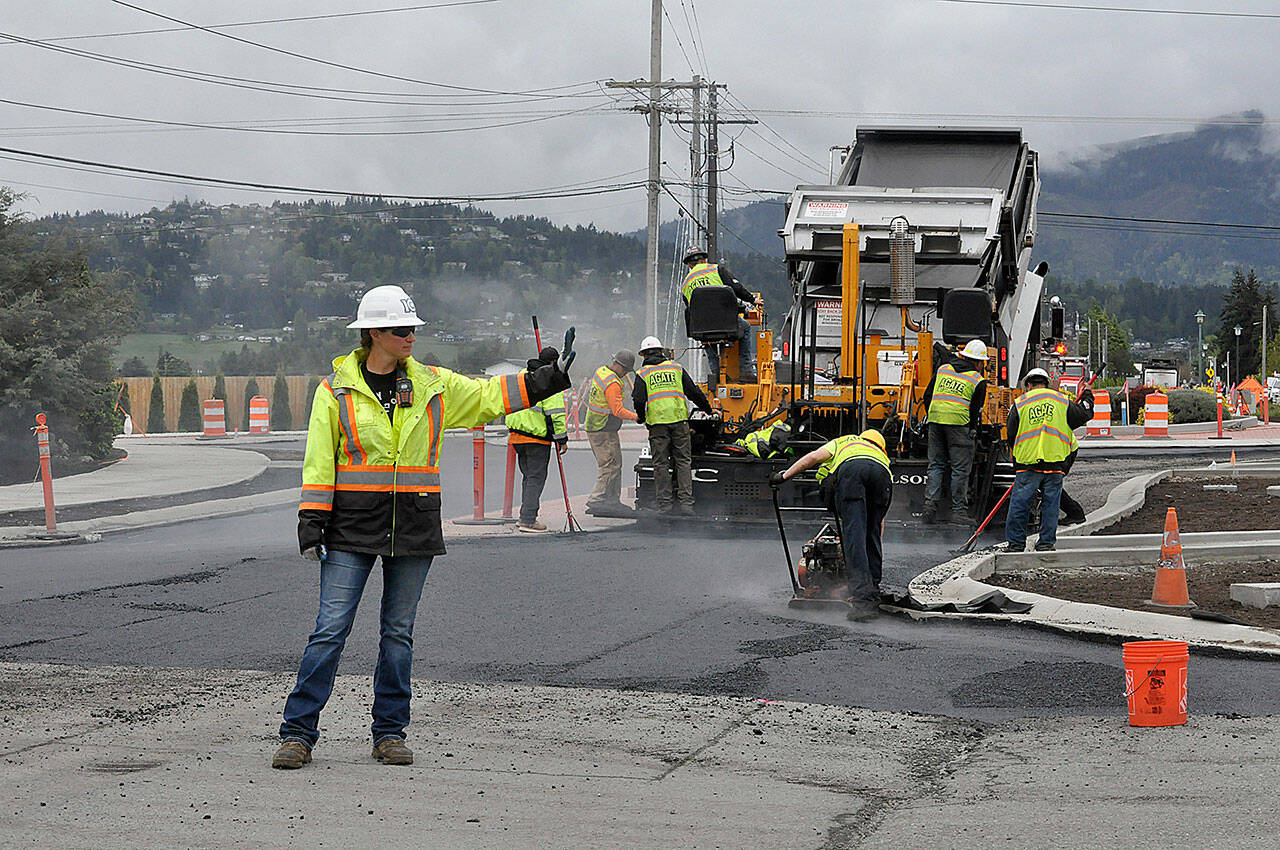 Sequim Gazette photo by Matthew Nash/ Sarah Bradley, a traffic control supervisor with Laborers Local 252, stops vehicles in Rock Plaza as paving work continues on the Sequim Avenue/Sequim-Dungeness Way roundabout on May 6.