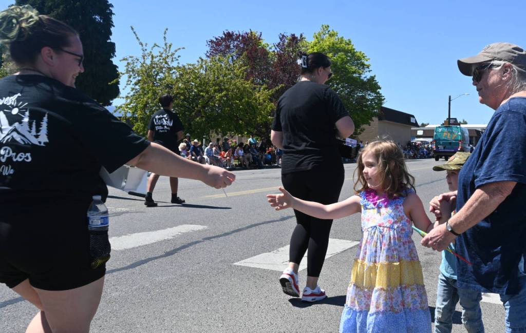 Sequim Gazette photo by Michael Dashiell / Evelyn MacDonald, almost 6, pictured with grandmother Teresa, both of Sequim, get some tasty candy handouts at the Sequim irrigation Festival Grand Parade on Saturday.