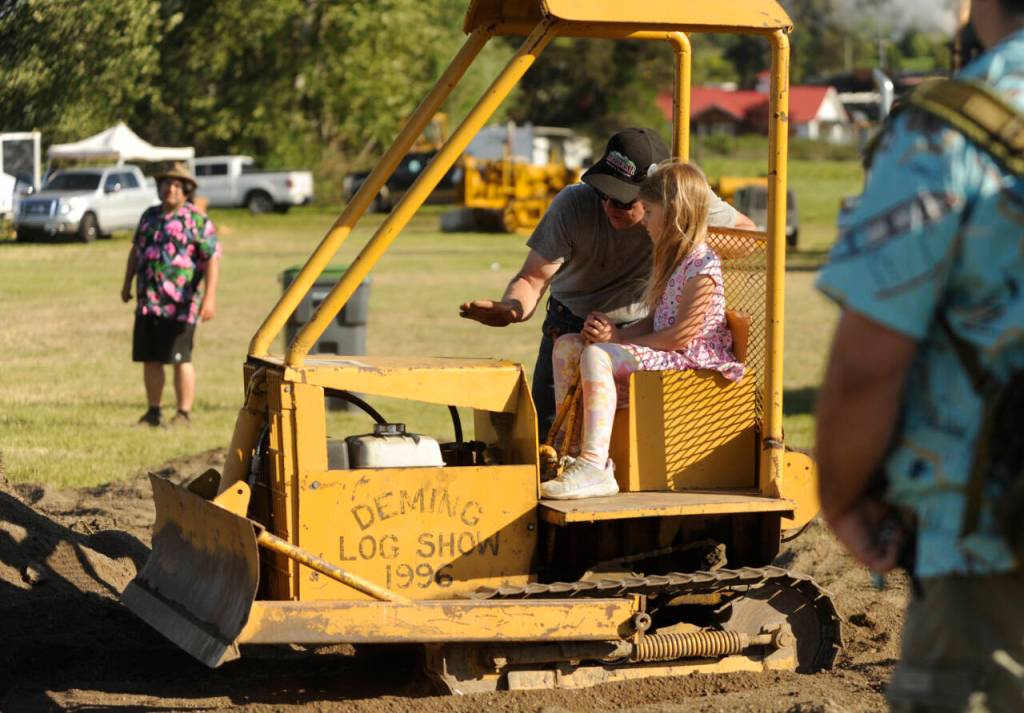 Sequim Gazette photo by Michael Dashiell / Nelson Bekkevar helps 7-year-old Marina Eliel of Diamond Point move some dirt at the annual Sequim Logging Show on Saturday afternoon.
