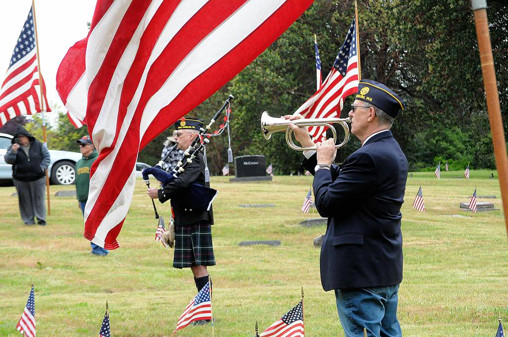 Sequim Gazette photo by Matthew Nash/ Rick McKenzie plays Amazing Grace as Paul Renick, finance officer for American Legion Post 62, stands at attention on May 27.