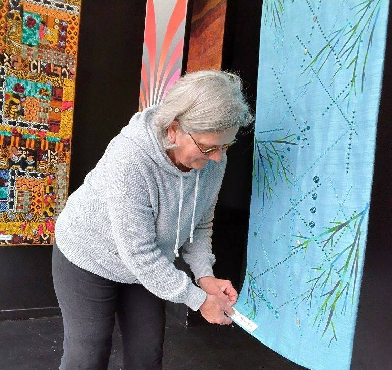 Photo courtesy of Peninsula Fiber Artists 
Port Townsend artist Sue Gale hangs one of the 16 x 60-inch banners now on display in the Peninsula Fiber Artists Fiber Habit walk-by exhibit at 675 Tyler St., Port Townsend. Most pieces in the exhibit are available for purchase directly from the artists.