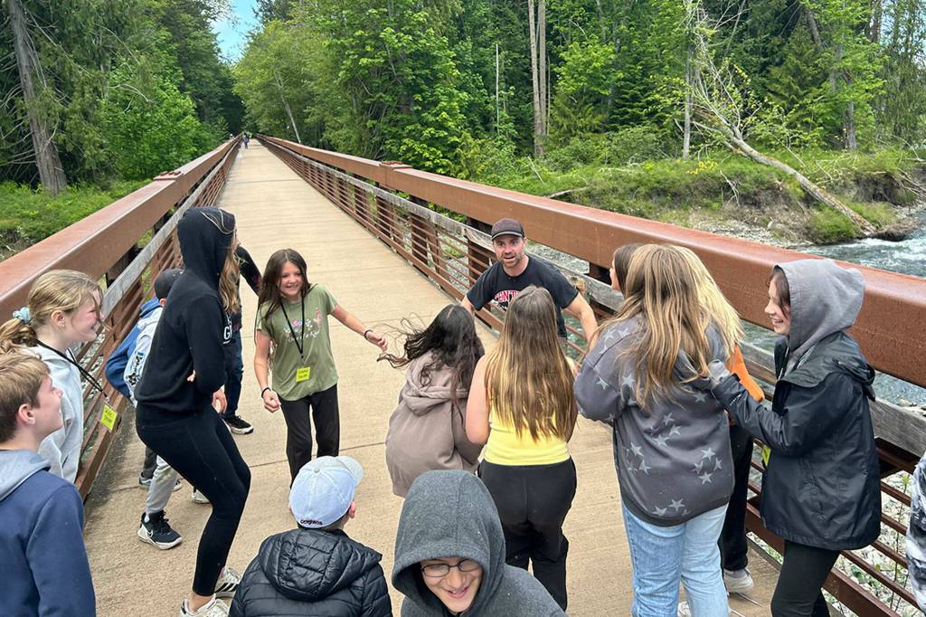 Sequim Gazette photo by Matthew Nash/ Powell Jones, Jamestown SKlallam Tribes land stewardship manager, and a group of Sequim sixth graders test the Dungeness River Railroad Bridge for its flexibility during a field trip on May 29 by jumping up and down.