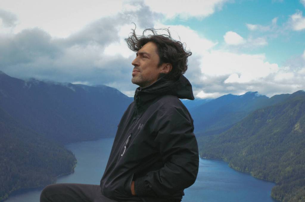 Sequim Gazette photo by Elijah Sussman / Ian Maksin is seated over Lake Crescent at Storm King viewpoint on a recent hike.