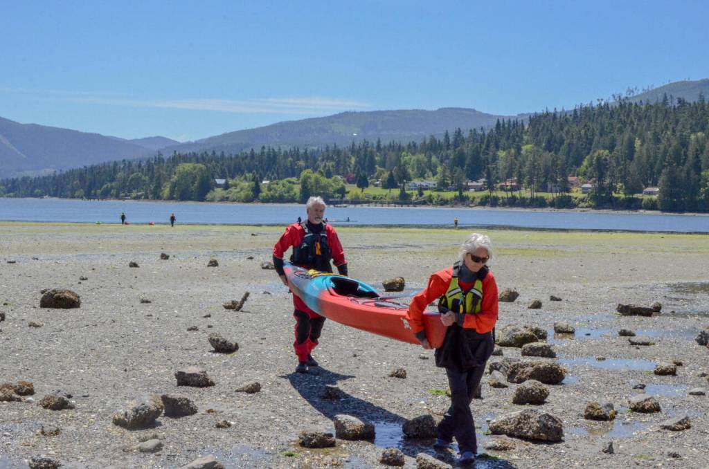 Sequim Gazette photo by Elijah Sussman / Lee Olsen (front) and Ed Urbanski carry their kayak up the beach at John Wayne Marina on June 6.