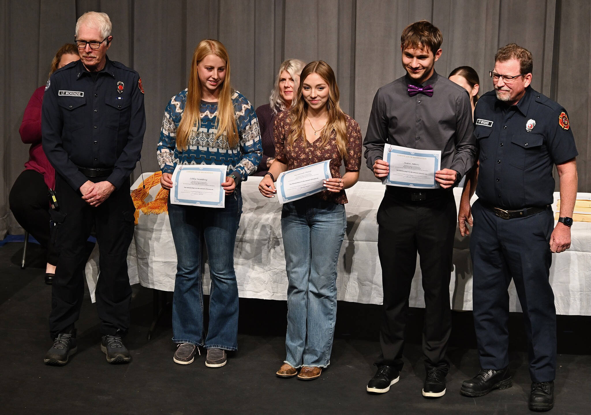 Photos by Jay Cline
At Sequim High Schools Scholarship Night on June 5, Sequim High seniors (from left) Libby Swanberg, Susannah Sharp and Aiden Albers receive Dale Kruse Memorial Scholarship funds from John McKenzie (far left) and John Brygider from Clallam County Fire District 3.
