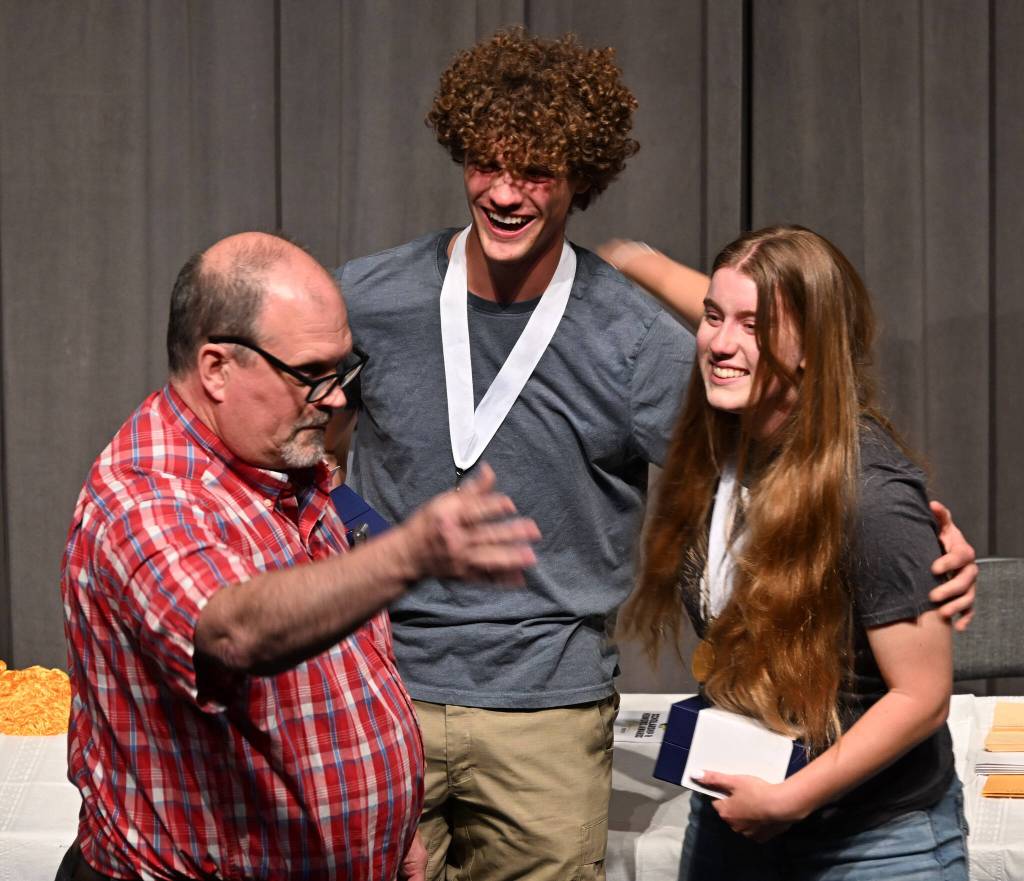 Shipley Center executive director Michael Smith, left, presents Sequim High seniors Samuel Stewart and Krista Charters with scholarships from the organization at SHSs Scholarship Night on June 5.