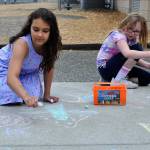 Sequim Gazette photo by Matthew Nash/ Fourth graders Nevaeda Steele and Abigail McBride add to the sidewalk chalk art display on June 11 at Helen Hallers Field Day. The girls said they were having a lot of fun during the annual event.